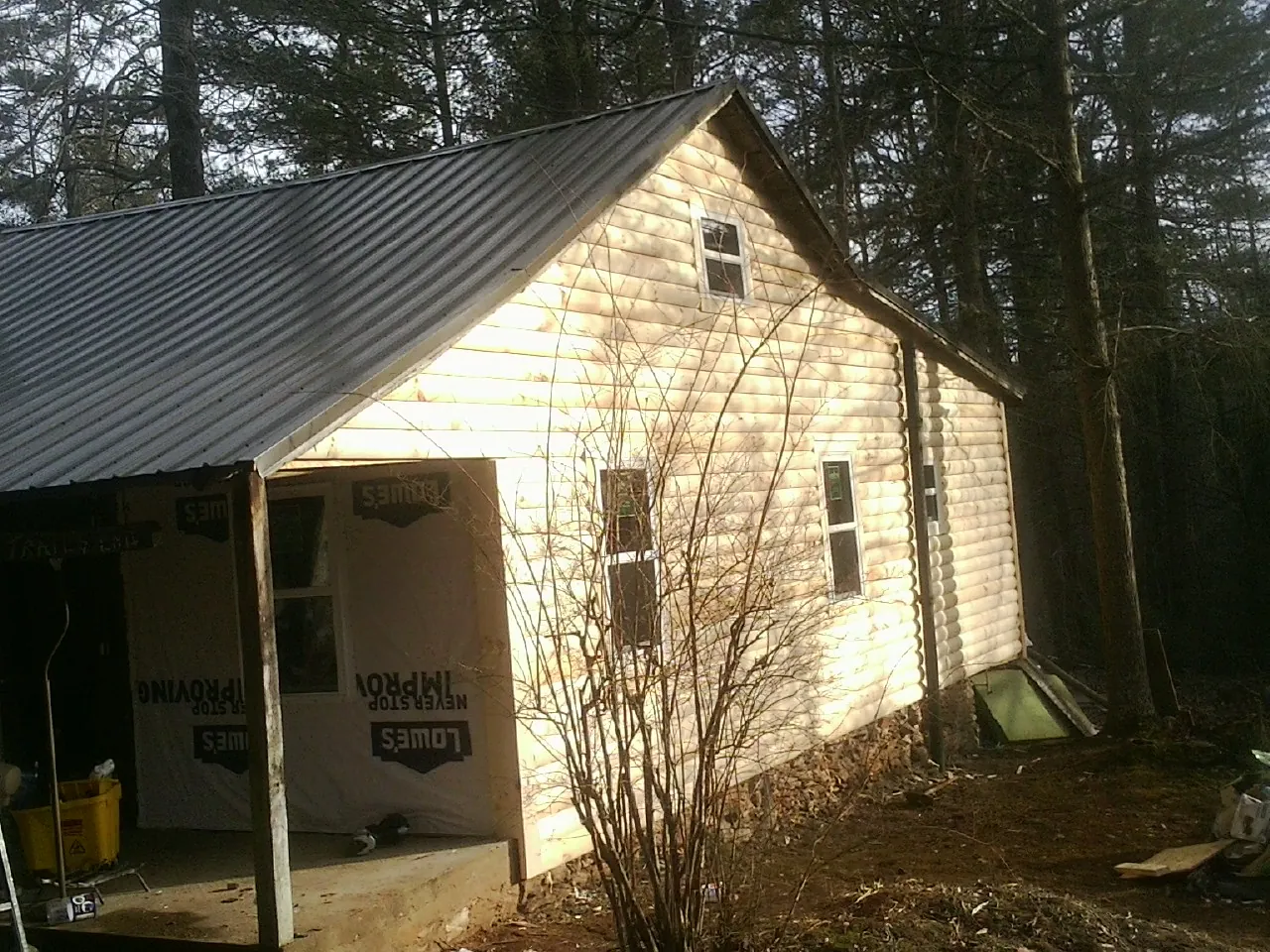 Log siding gable end under a dark metal roof edge in Randolph