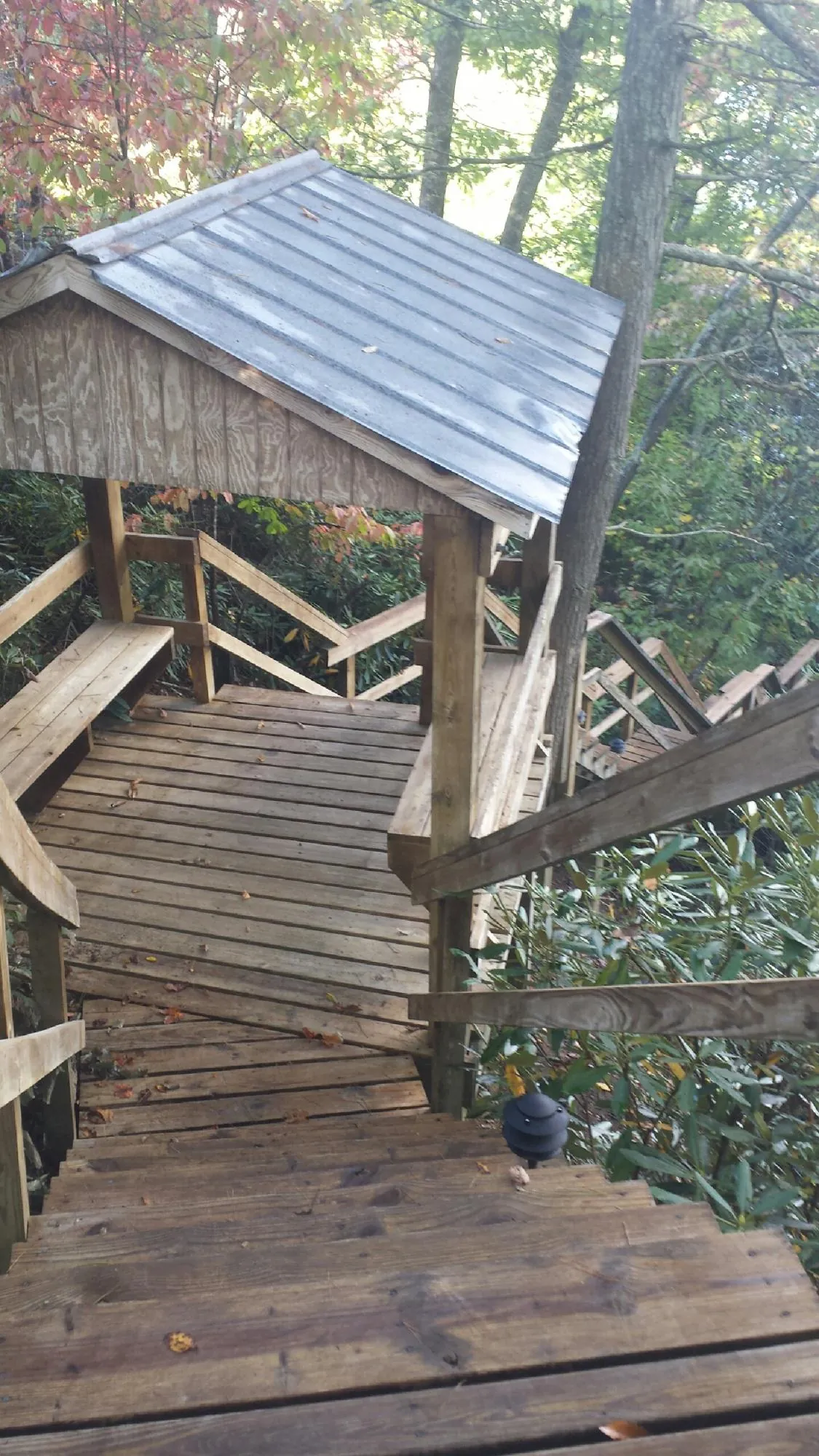 Metal roofed shelter over wooden steps on a wooded walkway — Skylight Repair & Installation work by our crew in Randolph